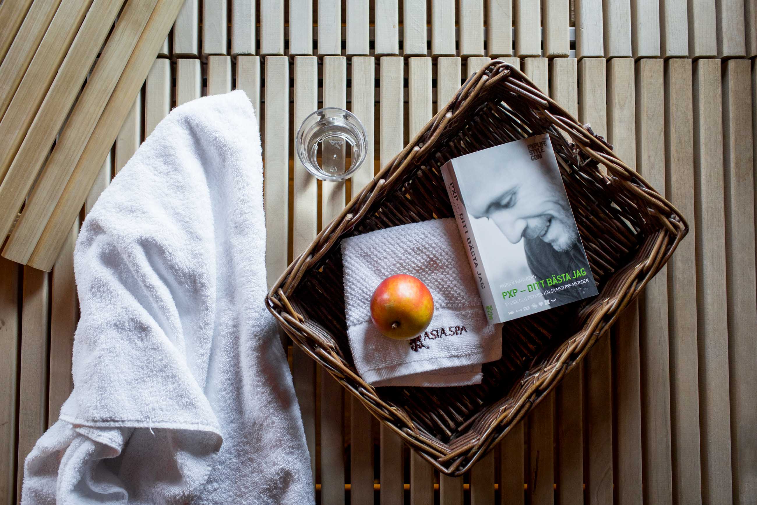 Korg med bok, äpple och handduk i bastuoasen på Asia Spa