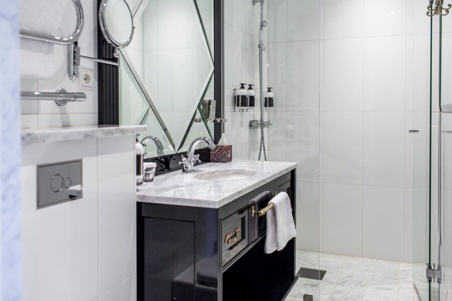 Badrummet är klassiskt inrett med marmorgolv, takstuckatur och högblank svart badrumsinredning.